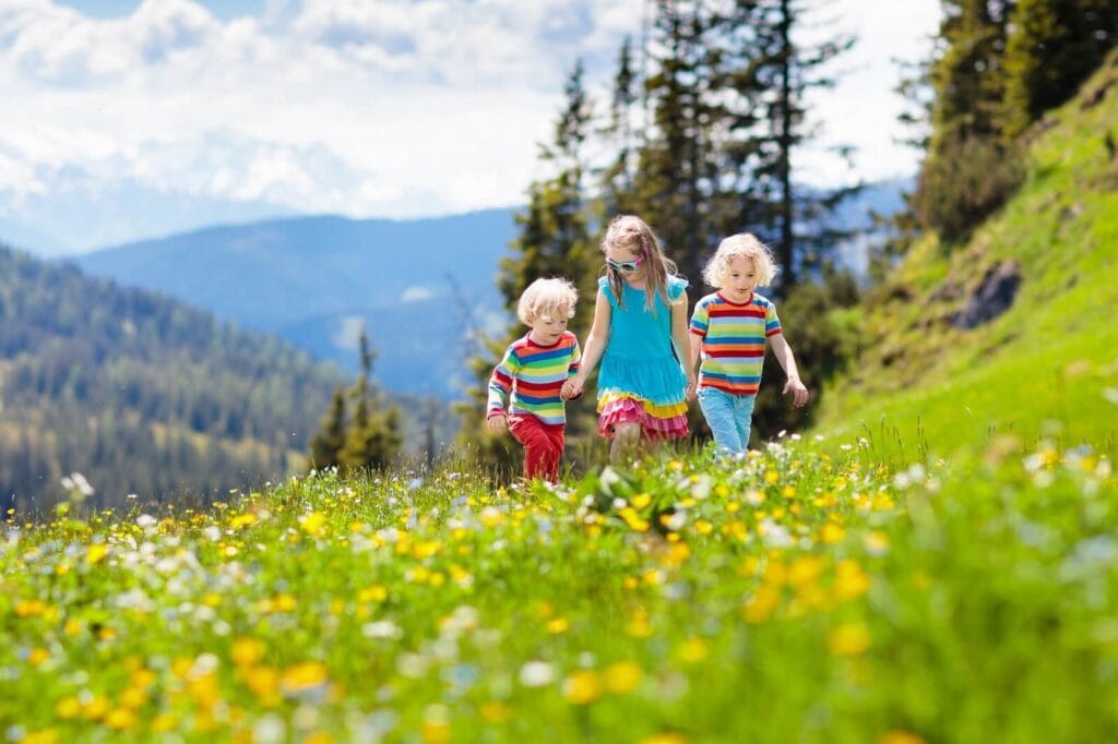 Bambini che corrono su un prato fiorito in montagna.